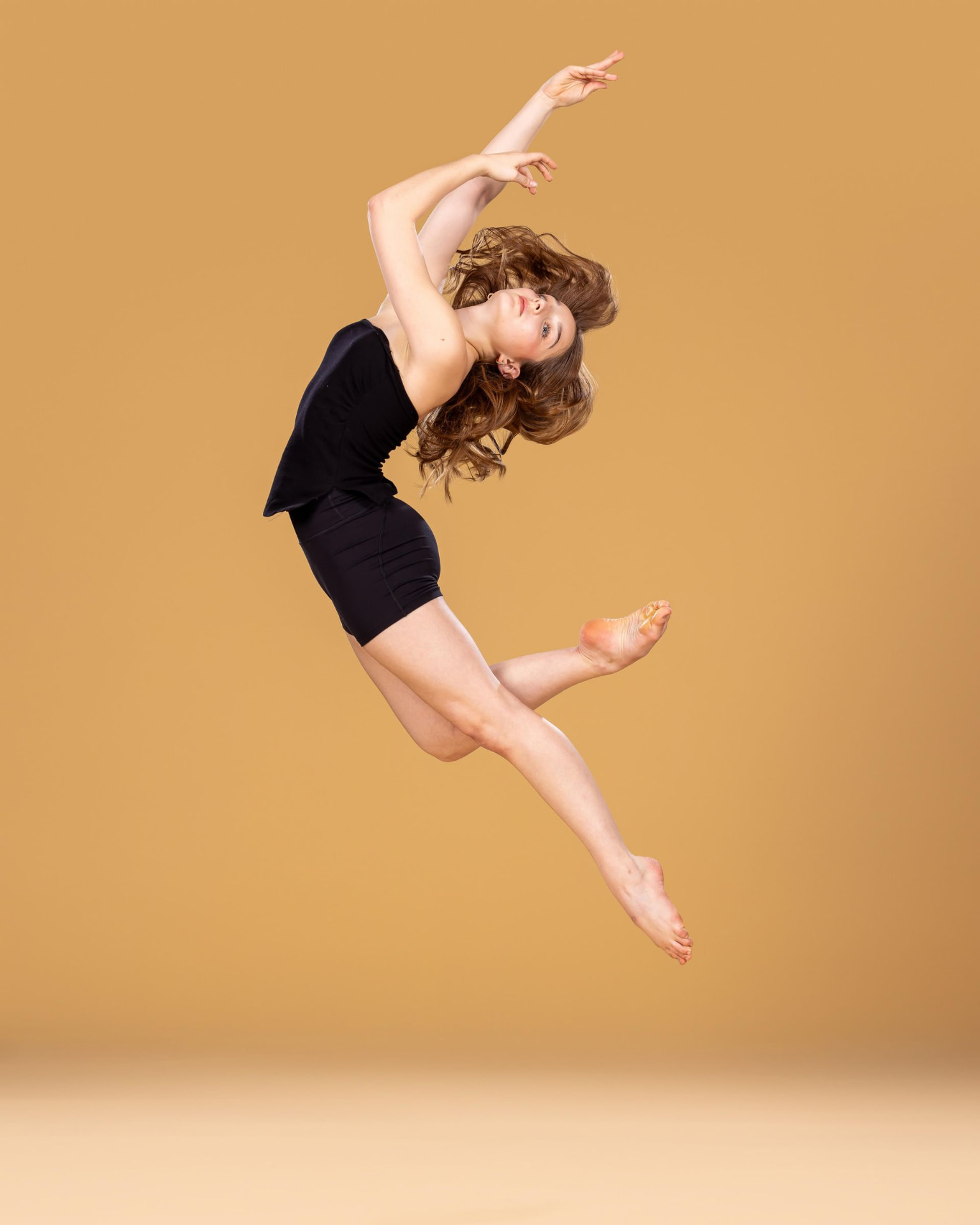 Dancer leaping in black against a gold background